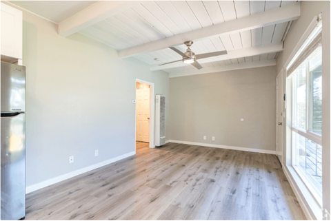an empty living room with wood floors and a ceiling fan